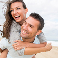 Young man and woman hugging and laughing on the beach