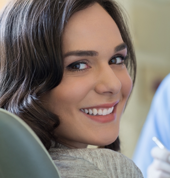 Woman in dental chair smiling after periodontal treatment