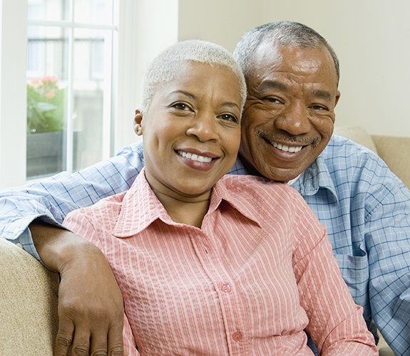 Man and woman smiling after dental implant supported tooth replacement