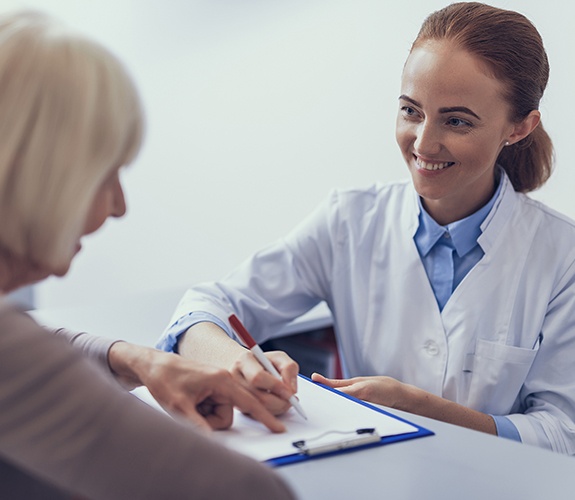 Dental team member helping patient review dental insurance forms