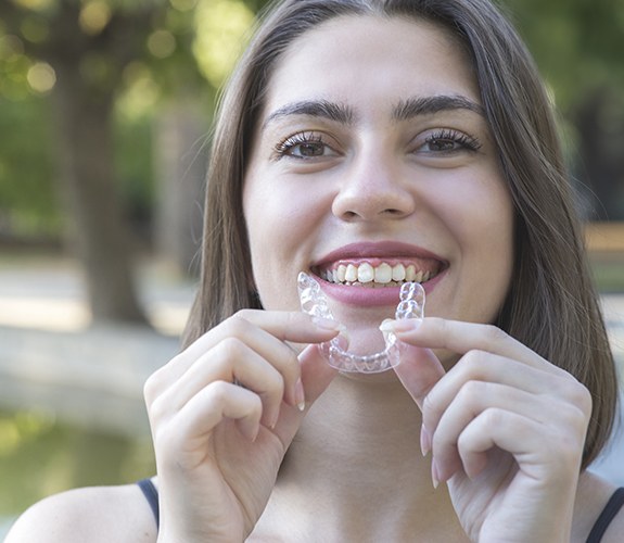 Smiling woman holding an Clear Aligners tray