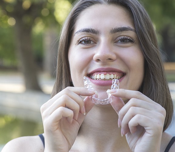 Smiling woman holding an Invisalign tray