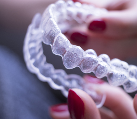 Person holding up an Invisalign aligner tray