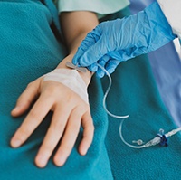Person inserting an IV into a patient’s arm