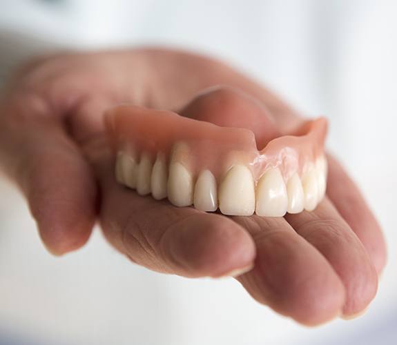 Hand holding a full denture