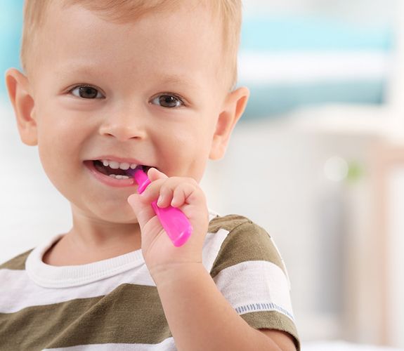 Little boy brushing his teeth with pink toothbrush