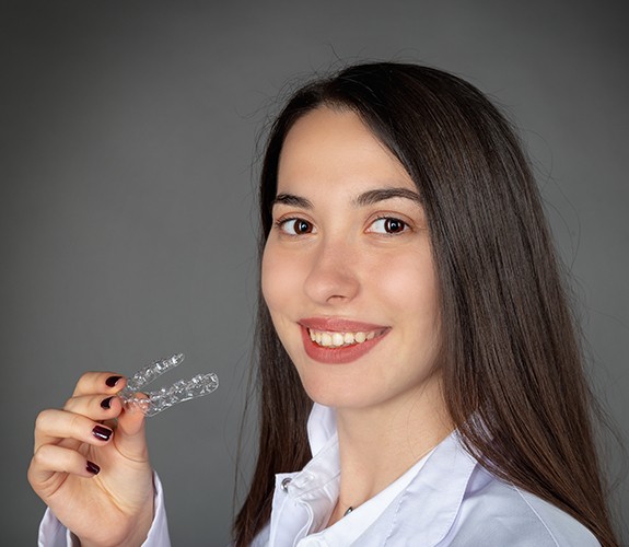 Woman holding an Invisalign clear braces tray