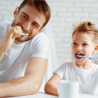 Man and little boy brushing their teeth