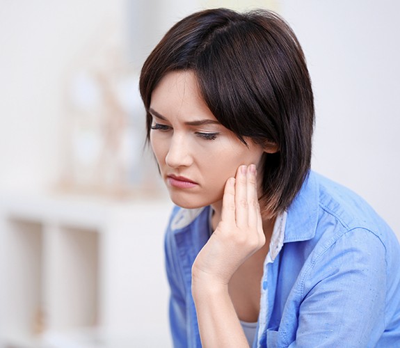 Woman in need of T M J treatment holding jaw