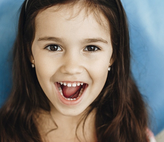 Girl showing her teeth after restorative dentistry procedure