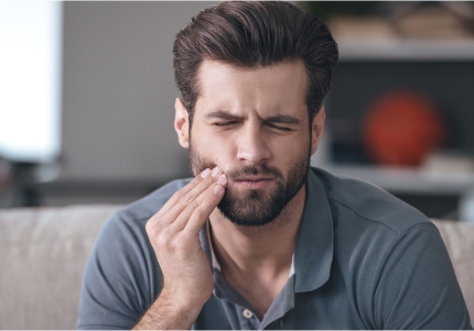 Woman in need of emergency dentistry holding cheek