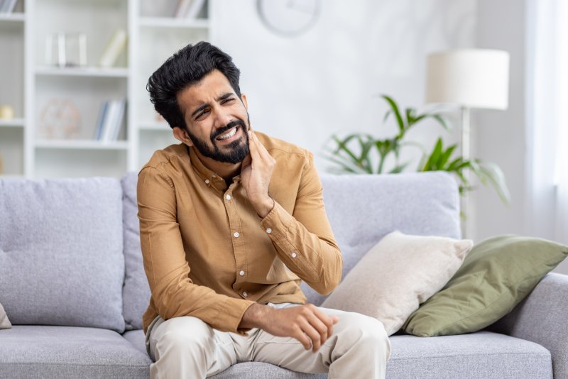 man sitting on a couch in terrible tooth pain